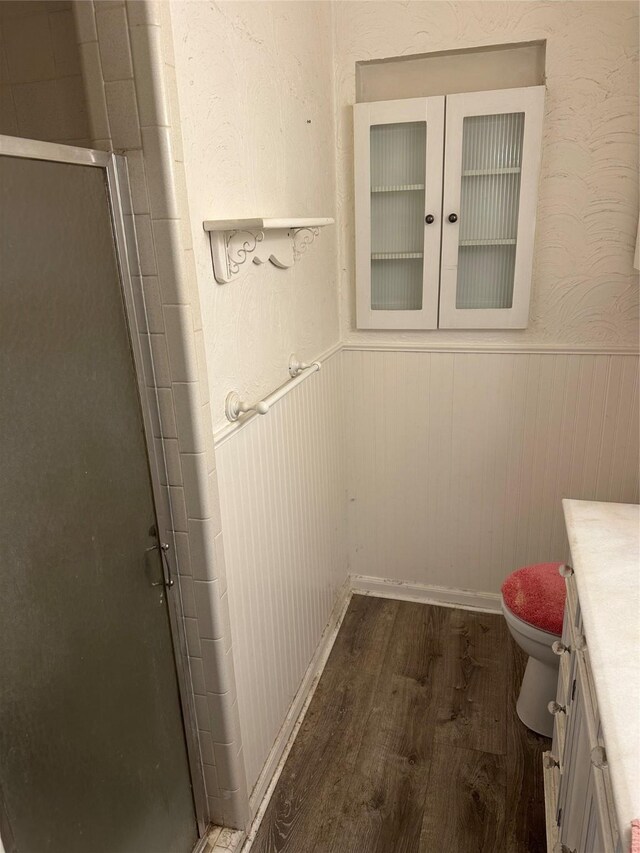 2410 Asbury St, Brownwood, TX 76801 - bathroom featuring vanity, wood finished floors, wainscoting, a stall shower, and toilet