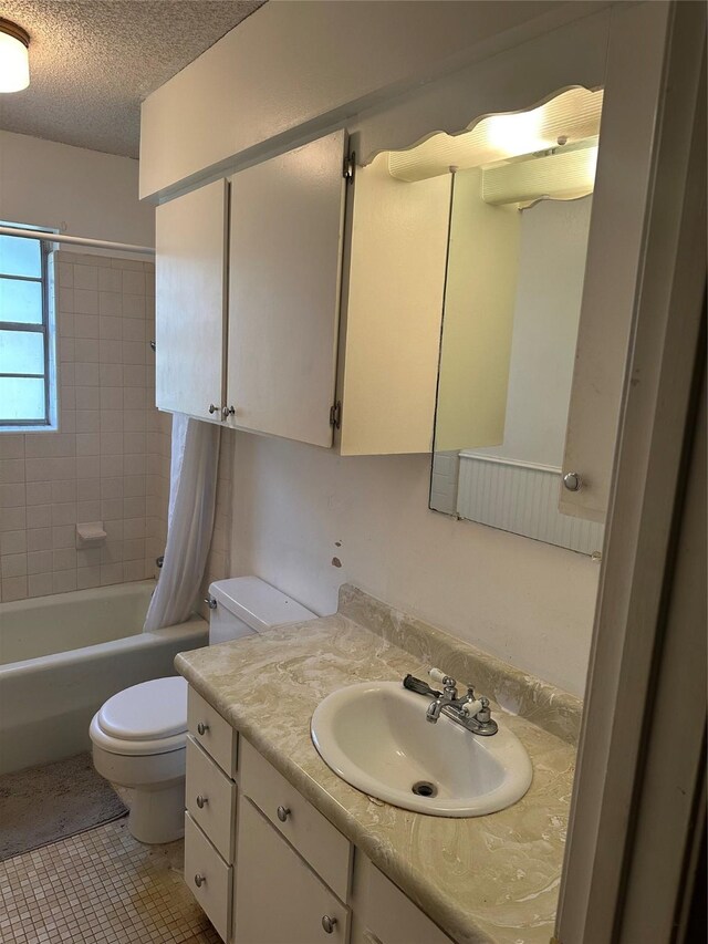 2410 Asbury St, Brownwood, TX 76801 - full bath featuring toilet, vanity, shower / tub combo, a textured ceiling, and tile patterned floors
