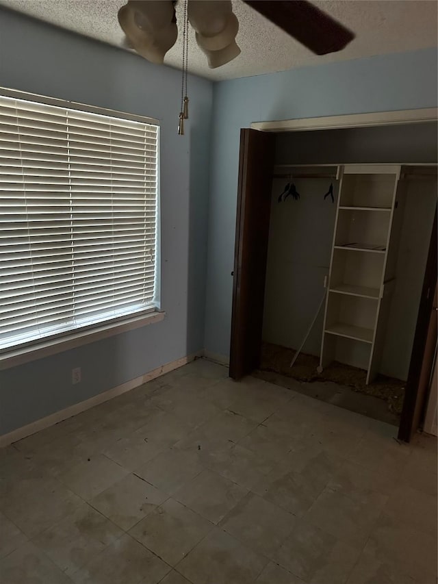 2410 Asbury St, Brownwood, TX 76801 - unfurnished bedroom featuring a textured ceiling, a closet, a ceiling fan, and baseboards