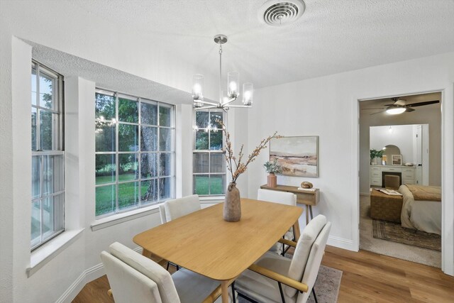 6304 Circleview Dr, Haltom City, TX 76180 - dining space with wood finished floors, a chandelier, a fireplace, baseboards, and a textured ceiling