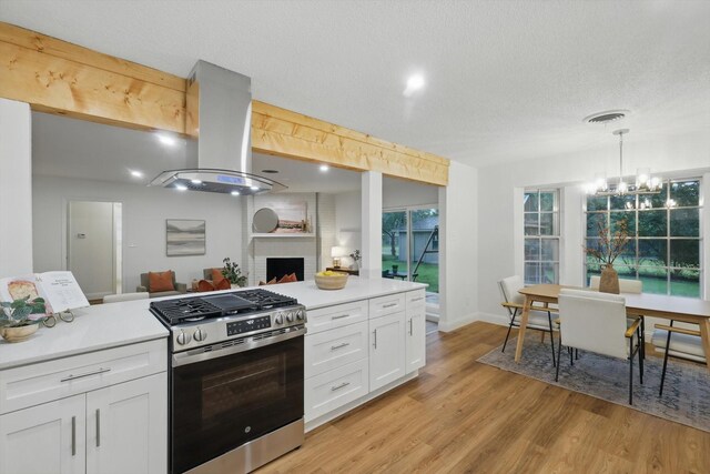 6304 Circleview Dr, Haltom City, TX 76180 - kitchen with stainless steel range with gas stovetop, island range hood, white cabinets, a brick fireplace, and light countertops