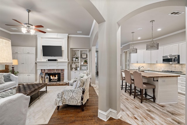 1229 Comanche Dr, Allen, TX 75013 - living area with arched walkways, crown molding, ceiling fan, recessed lighting, and light wood-style floors
