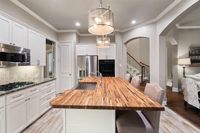 1229 Comanche Dr, Allen, TX 75013 - dining area featuring arched walkways, stairway, light wood-type flooring, recessed lighting, and crown molding