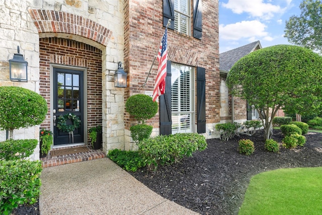 1229 Comanche Dr, Allen, TX 75013 - view of exterior entry featuring brick siding and a shingled roof
