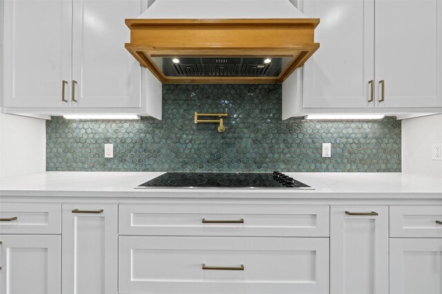 10917 Granada Dr, Waco, TX 76708 - kitchen with premium range hood, black electric cooktop, light countertops, white cabinetry, and backsplash