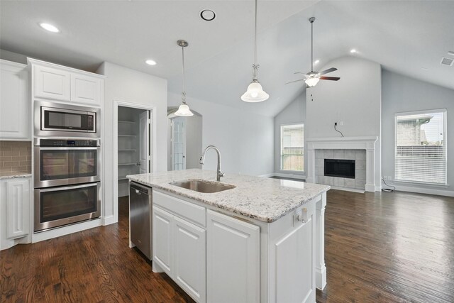 2004 Long Park Ave, Prosper, TX 75078 - kitchen with a sink, appliances with stainless steel finishes, vaulted ceiling, white cabinets, and a tiled fireplace