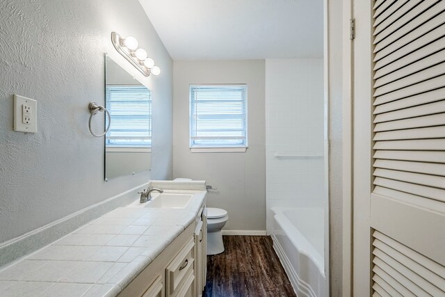 5729 Wales Ave, Fort Worth, TX 76133 - bathroom with wood finished floors, toilet, vanity, baseboards, and bathtub / shower combination