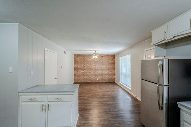 5729 Wales Ave, Fort Worth, TX 76133 - kitchen with freestanding refrigerator, brick wall, ceiling fan, dark wood-style floors, and white cabinetry