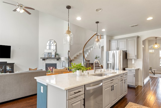 1008 Cason Falls Rd, Mckinney, TX 75071 - kitchen with appliances with stainless steel finishes, a fireplace, dark wood-type flooring, ceiling fan, and arched walkways