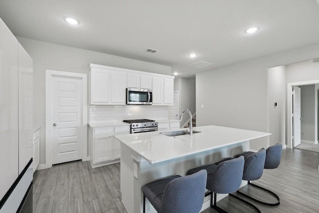 2321 Spring Side Dr, Royse City, TX 75189 - kitchen featuring appliances with stainless steel finishes, a sink, light wood-style floors, tasteful backsplash, and a breakfast bar area