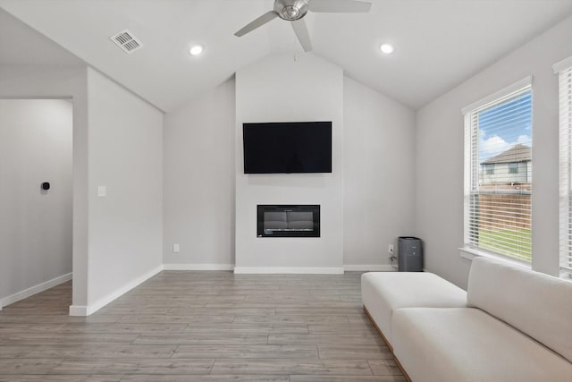 2321 Spring Side Dr, Royse City, TX 75189 - living room featuring light wood-style floors, vaulted ceiling, a ceiling fan, a glass covered fireplace, and baseboards