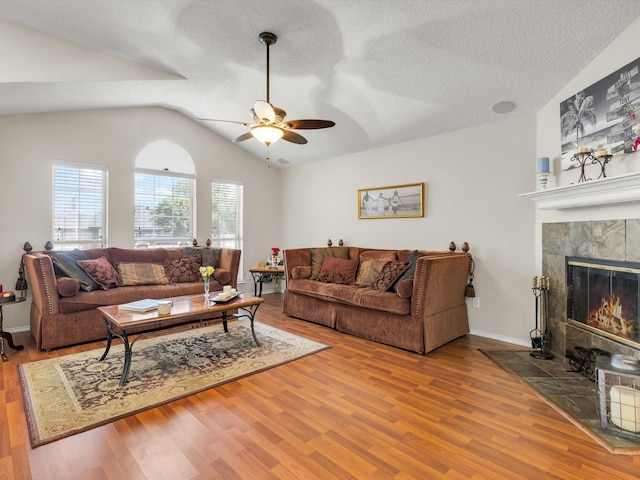 10117 High Bluff Dr, Fort Worth, TX 76108 - living room with ceiling fan, wood finished floors, vaulted ceiling, a tile fireplace, and a textured ceiling