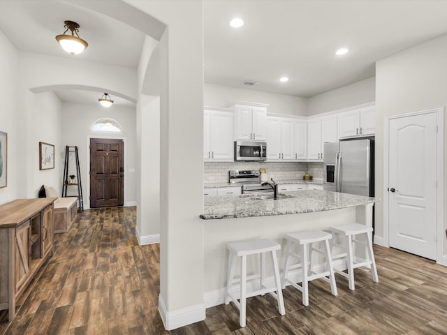 11716 Pistachio Trl, Fort Worth, TX 76108 - kitchen featuring appliances with stainless steel finishes, arched walkways, a sink, dark wood-style flooring, and white cabinetry