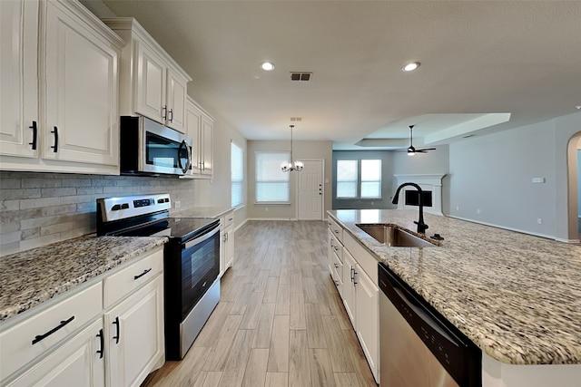 928 Dove Cv, Argyle, TX 76226 - kitchen featuring appliances with stainless steel finishes, a sink, a fireplace, light wood-style flooring, and recessed lighting