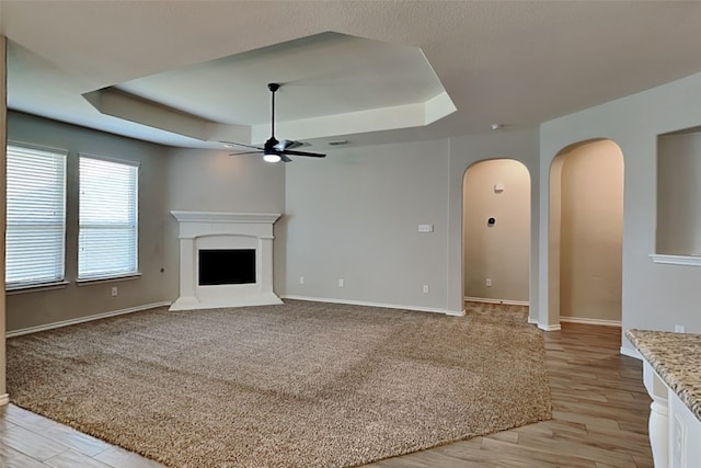 928 Dove Cv, Argyle, TX 76226 - unfurnished living room with a tray ceiling, a ceiling fan, arched walkways, and baseboards