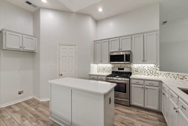 1401 Superior Dr, Flower Mound, TX 75028 - kitchen featuring appliances with stainless steel finishes, light wood-style flooring, backsplash, a towering ceiling, and recessed lighting