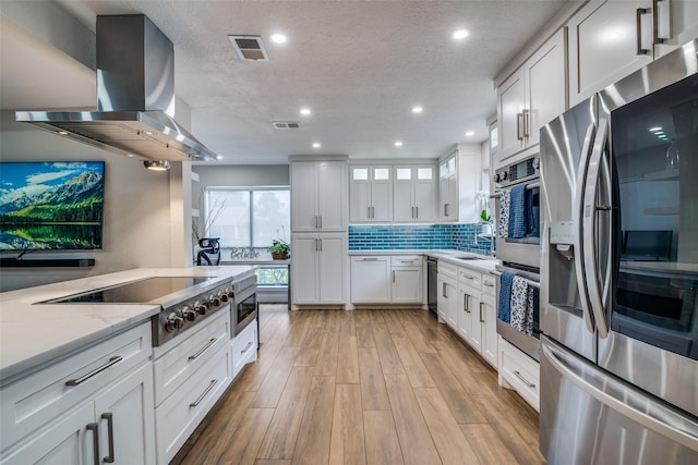 1316 Devonshire Ln, Mesquite, TX 75150 - kitchen featuring appliances with stainless steel finishes, island exhaust hood, white cabinets, light wood finished floors, and light stone counters