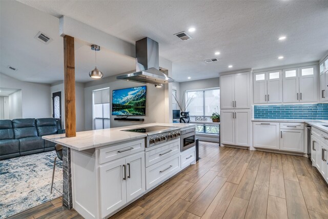 1316 Devonshire Ln, Mesquite, TX 75150 - kitchen featuring island exhaust hood, stainless steel gas stovetop, light wood-style flooring, white cabinetry, and light stone countertops