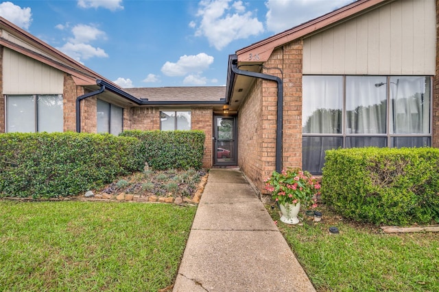 1316 Devonshire Ln, Mesquite, TX 75150 - view of exterior entry featuring brick siding, a lawn, and a shingled roof