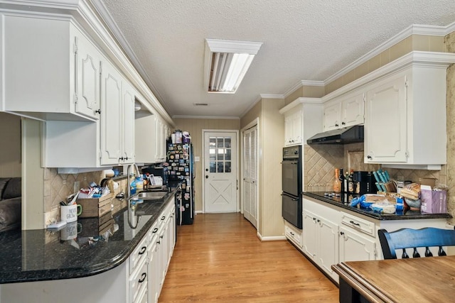 2916 Lafayette St, Corsicana, TX 75110 - kitchen with a sink, white cabinetry, under cabinet range hood, light wood-style floors, and a textured ceiling