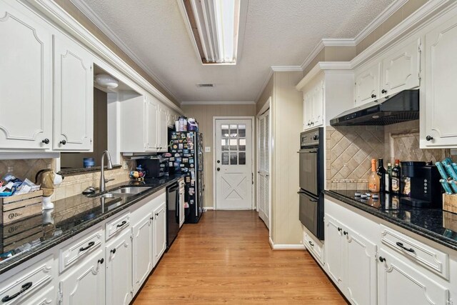 2916 Lafayette St, Corsicana, TX 75110 - kitchen with under cabinet range hood, black appliances, a sink, white cabinets, and crown molding