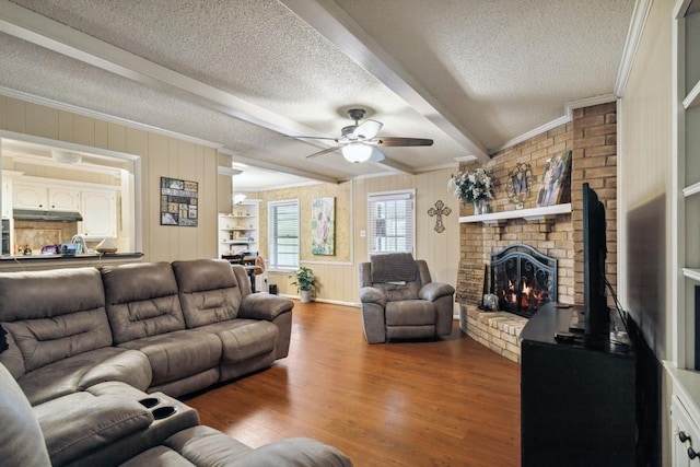 2916 Lafayette St, Corsicana, TX 75110 - living room featuring a textured ceiling, ceiling fan, a fireplace, wood finished floors, and beam ceiling