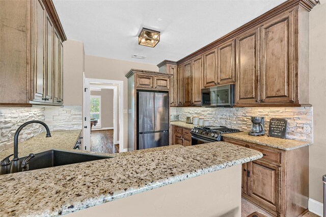 30 Tananger Springs Dr, Denison, TX 75021 - kitchen with appliances with stainless steel finishes, a sink, light stone counters, and backsplash