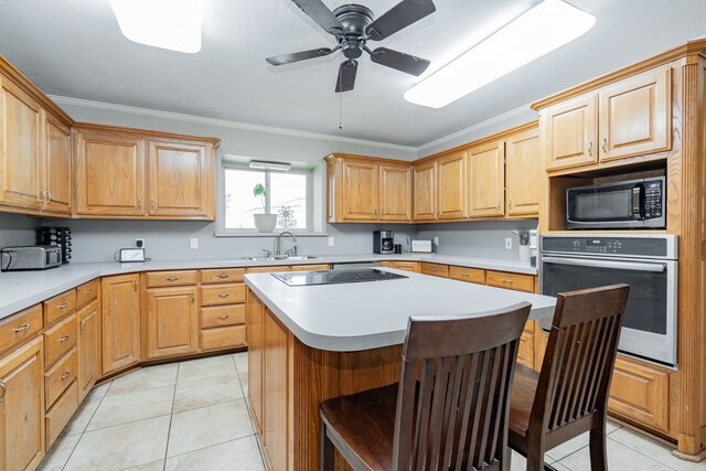 9390 Adams St, Terrell, TX 75160 - kitchen featuring stainless steel oven, a sink, ornamental molding, a breakfast bar, and ceiling fan