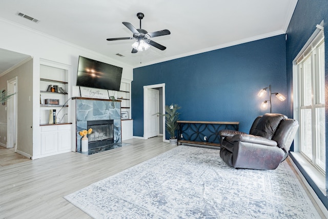 9390 Adams St, Terrell, TX 75160 - living room with ornamental molding, a ceiling fan, wood finished floors, built in shelves, and a tiled fireplace