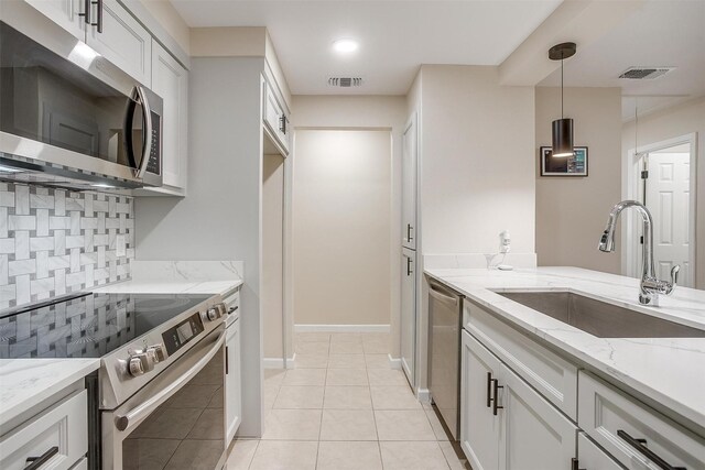 7013 Buttonwood Dr, Fort Worth, TX 76137 - kitchen featuring appliances with stainless steel finishes, a sink, tasteful backsplash, hanging light fixtures, and white cabinets