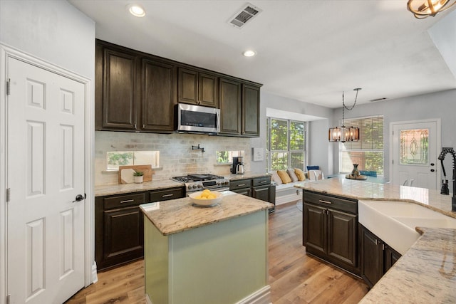 4710 Safe Harbour Dr, Arlington, TX 76016 - kitchen featuring stainless steel appliances, a sink, dark brown cabinetry, light stone counters, and decorative backsplash