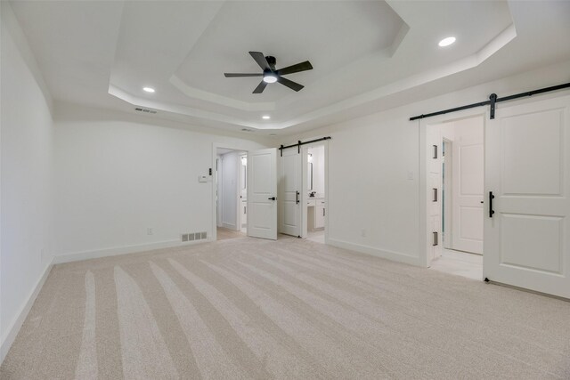 3620 Big Horn Trl, Plano, TX 75075 - unfurnished bedroom featuring a barn door, a raised ceiling, recessed lighting, light carpet, and baseboards