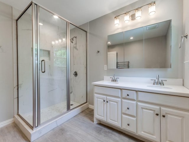 1135 La Mesa Dr, Richardson, TX 75080 - bathroom featuring a stall shower, double vanity, wood finished floors, and baseboards
