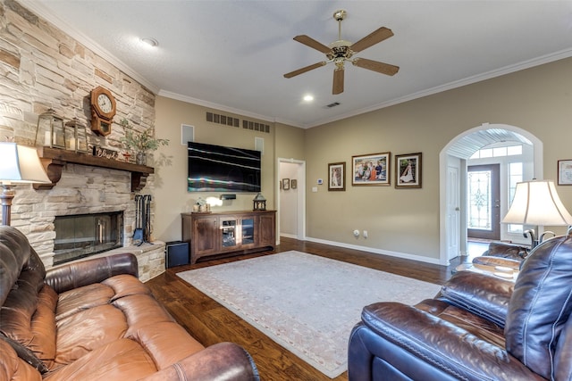 5891 Harmony Ranch Rd, Aubrey, TX 76227 - living area featuring a ceiling fan, wood finished floors, ornamental molding, a stone fireplace, and arched walkways