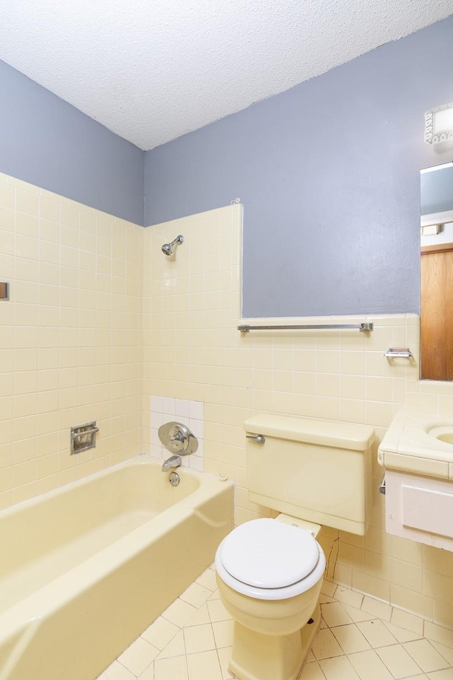 403 W China St, Brady, TX 76825 - bathroom with tile patterned floors, tile walls, toilet, shower / bathtub combination, and a textured ceiling