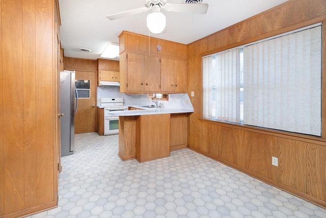 403 W China St, Brady, TX 76825 - kitchen featuring white electric range, under cabinet range hood, a peninsula, freestanding refrigerator, and a sink