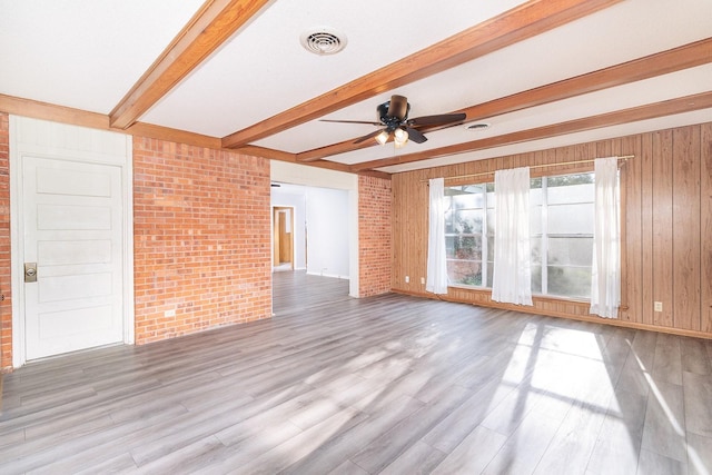 403 W China St, Brady, TX 76825 - unfurnished living room with brick wall, a ceiling fan, beam ceiling, light wood-style floors, and baseboards