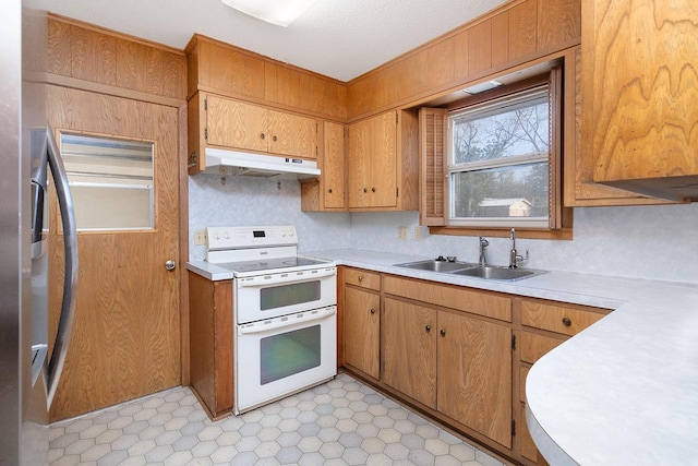 403 W China St, Brady, TX 76825 - kitchen featuring double oven range, under cabinet range hood, a sink, stainless steel refrigerator with ice dispenser, and light countertops