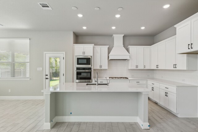 1105 Alaska, Forney, TX 75126 - kitchen featuring oven, custom exhaust hood, a sink, tasteful backsplash, and light wood-type flooring