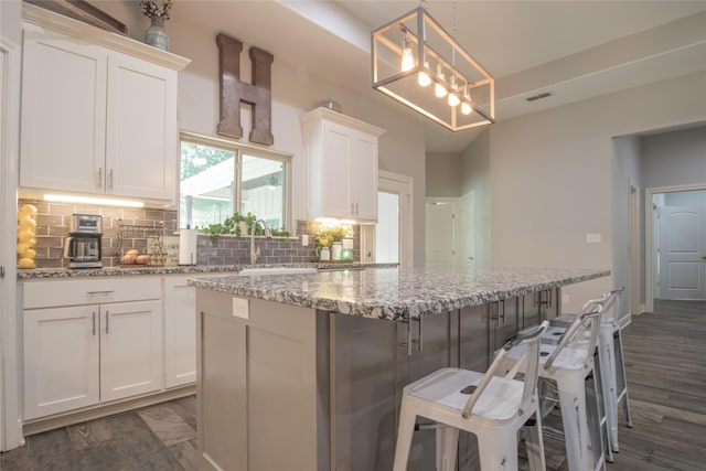 17294 Hidden Valley Ln, Flint, TX 75762 - kitchen with white cabinets, backsplash, a center island, light stone countertops, and a sink