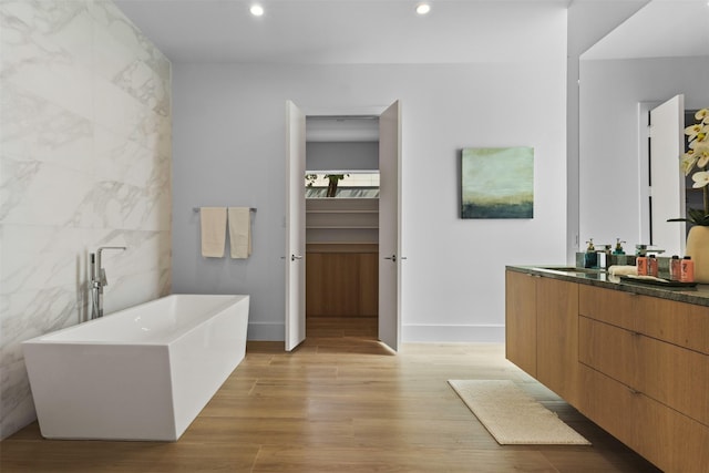 3941 Adrian Dr, Dallas, TX 75209 - full bathroom featuring vanity, a freestanding bath, wood finished floors, baseboards, and recessed lighting