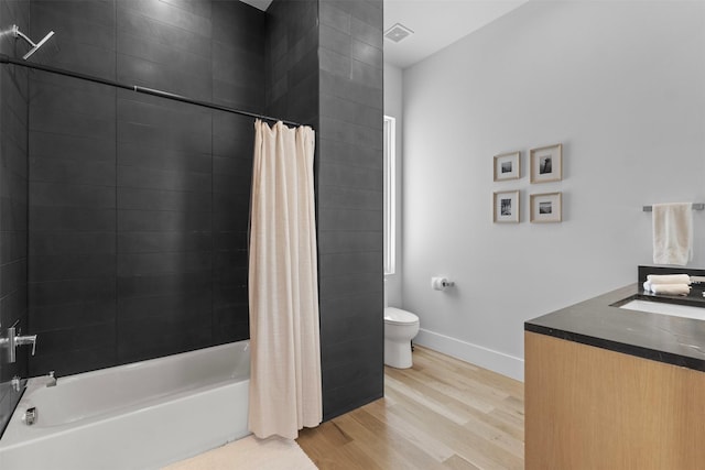 3941 Adrian Dr, Dallas, TX 75209 - bathroom featuring wood finished floors, toilet, shower / tub combo, vanity, and baseboards
