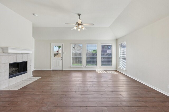 8208 Lonesome Spur Trl, Mckinney, TX 75070 - unfurnished living room featuring a ceiling fan, wood finished floors, a tiled fireplace, baseboards, and lofted ceiling