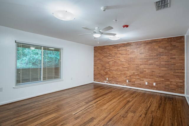 921 NW 9th St, Grand Prairie, TX 75050 - spare room with brick wall, wood finished floors, a ceiling fan, baseboards, and a smoke detector