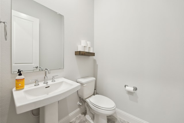 2560 Liverpool Ln, Carrollton, TX 75010 - bathroom featuring baseboards, toilet, marble finish floors, and a sink