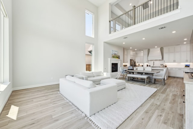 2560 Liverpool Ln, Carrollton, TX 75010 - living room with light wood-style floors, a towering ceiling, baseboards, and a glass covered fireplace