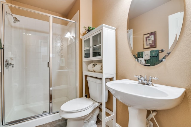 2345 Falls View Dr, Rockwall, TX 75087 - bathroom featuring toilet, a stall shower, a textured wall, and a sink