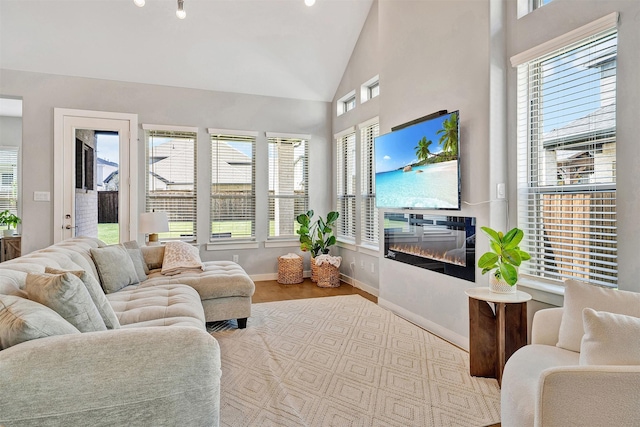 3580 Spruce Hills St, Frisco, TX 75033 - living room with plenty of natural light, a glass covered fireplace, baseboards, high vaulted ceiling, and wood finished floors