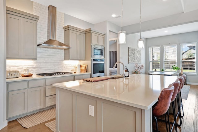 3580 Spruce Hills St, Frisco, TX 75033 - kitchen with stainless steel appliances, wall chimney exhaust hood, light wood-style floors, tasteful backsplash, and gray cabinetry
