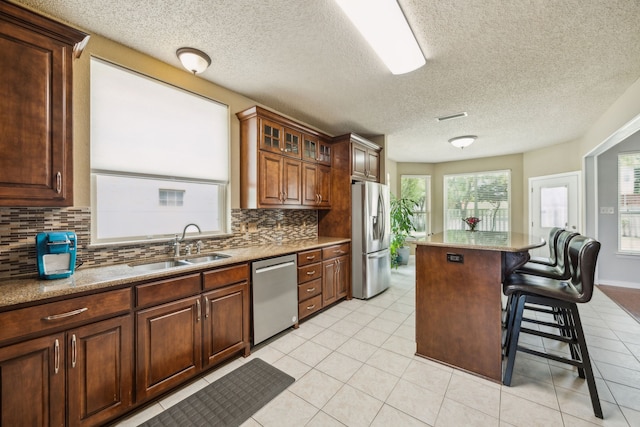 4433 Buchanan Dr, Plano, TX 75024 - kitchen featuring appliances with stainless steel finishes, a sink, tasteful backsplash, a breakfast bar, and a kitchen island
